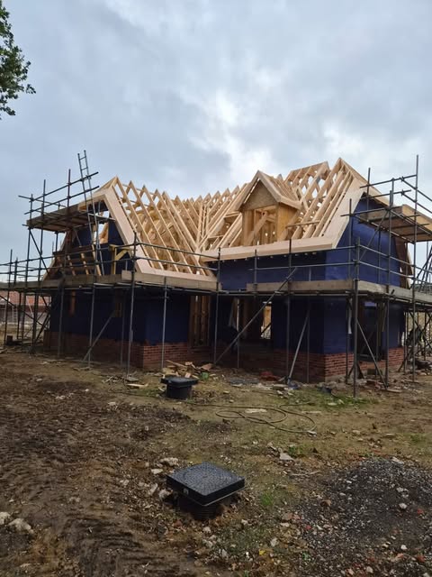 Stick-built timber frame house with attic trusses and dormers under scaffold